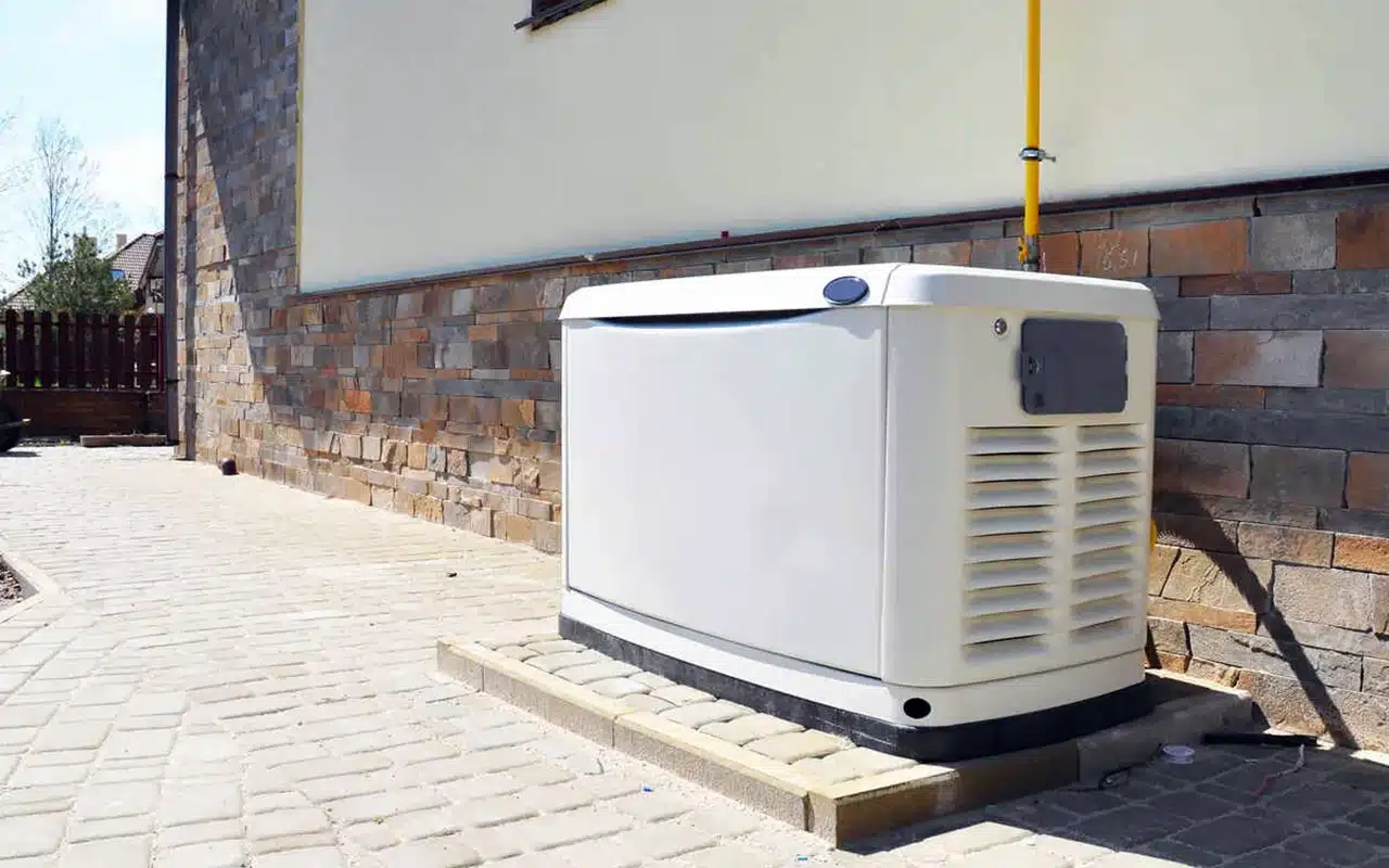 Home backup generator installed next to a brick house for power supply