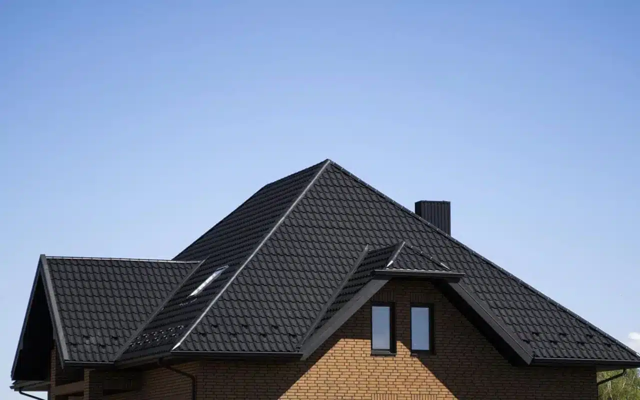 Modern brick house with black metal roof under blue sky