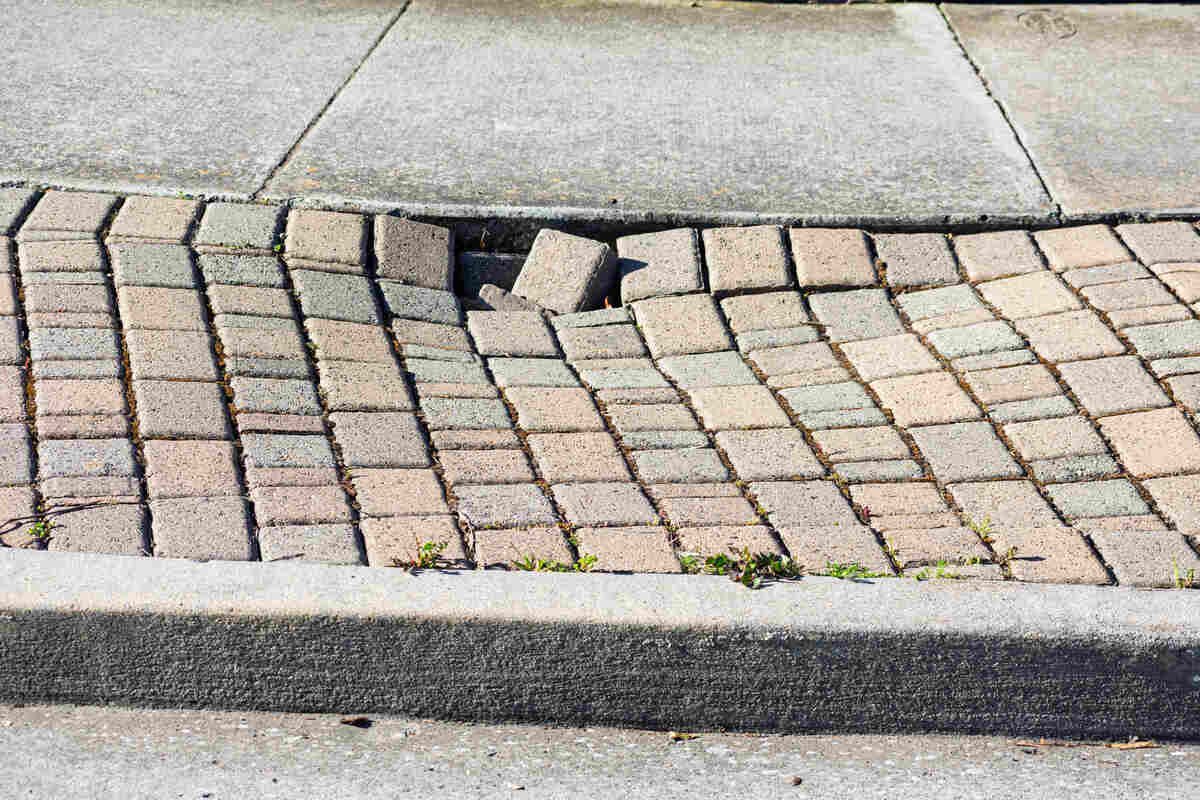 Uneven paving stone sidewalk with damaged bricks