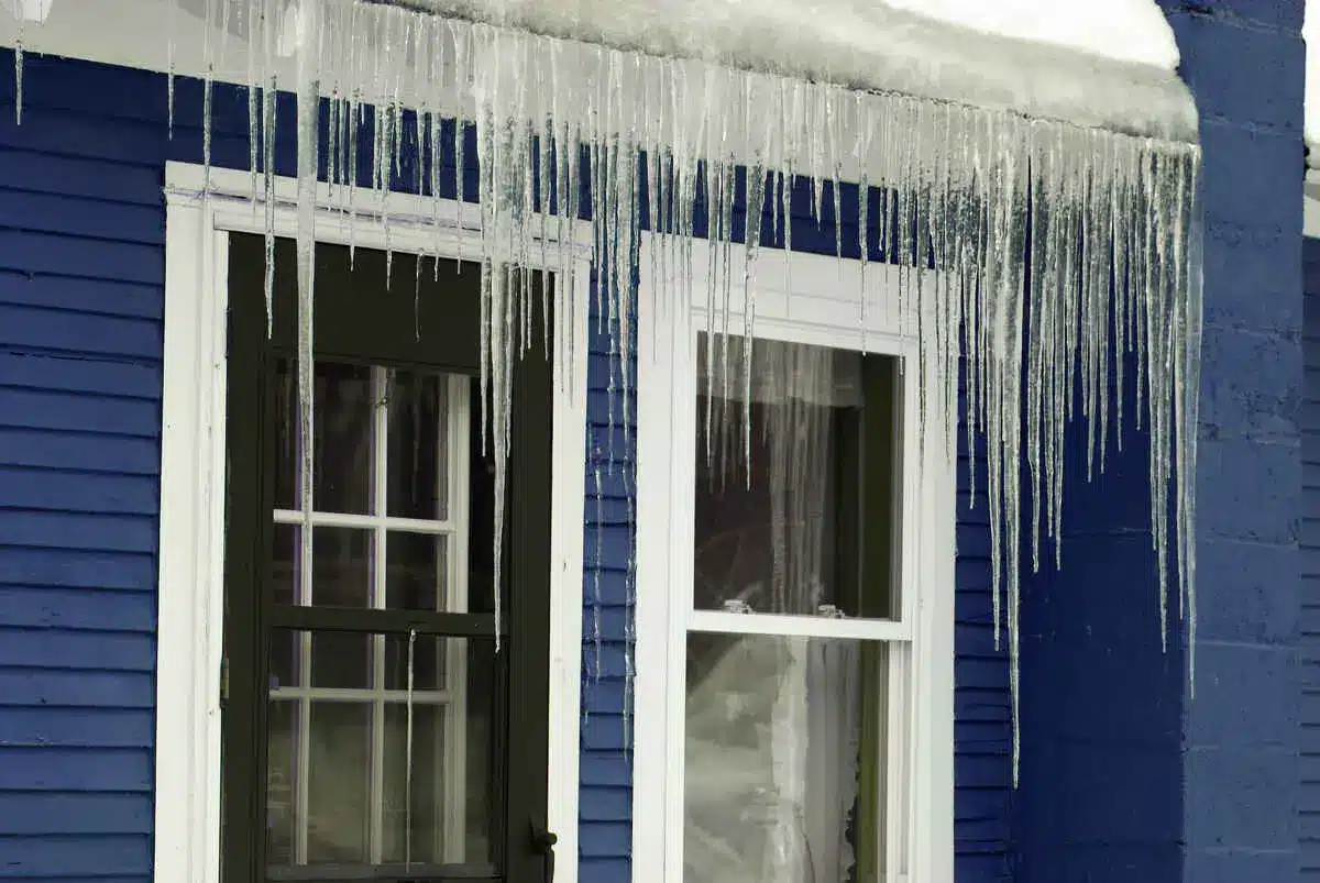 Icicles hanging from roof of blue house in winter