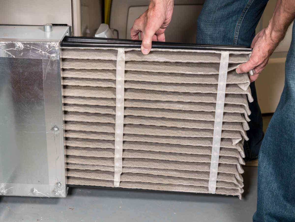 Person changing dirty HVAC air filter in residential unit