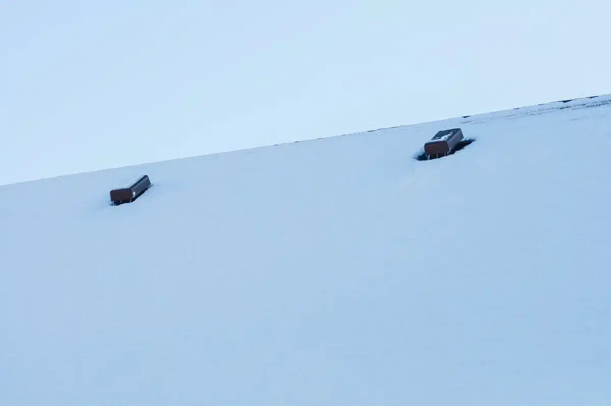 Snow-covered roof with two visible chimney tops
